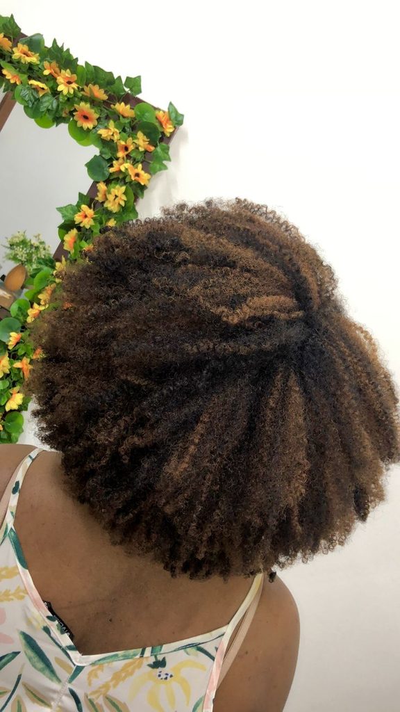 Black woman with lighter highlights throughout tightly coiled natural hair