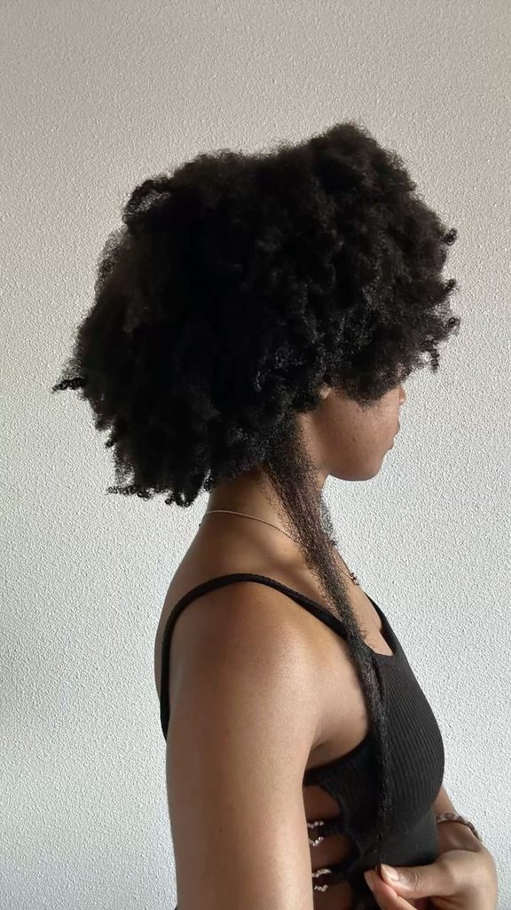 Woman showing the length of her healthy natural 4C hair