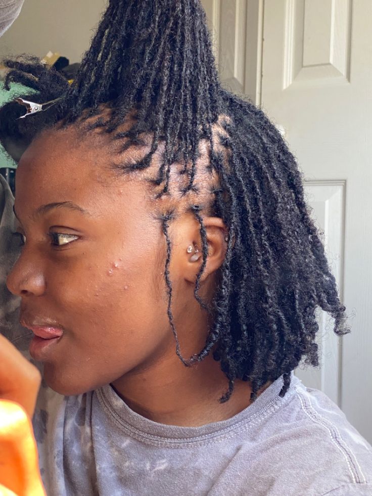 Woman with tightly coiled 4C hair wearing small natural locs