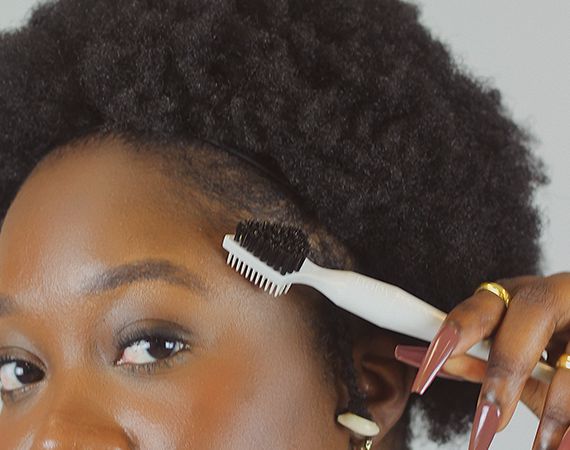 Woman gently styling the edges of natural 4C hair