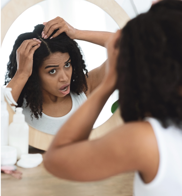 woman assessing her hair in the mirror before coloring