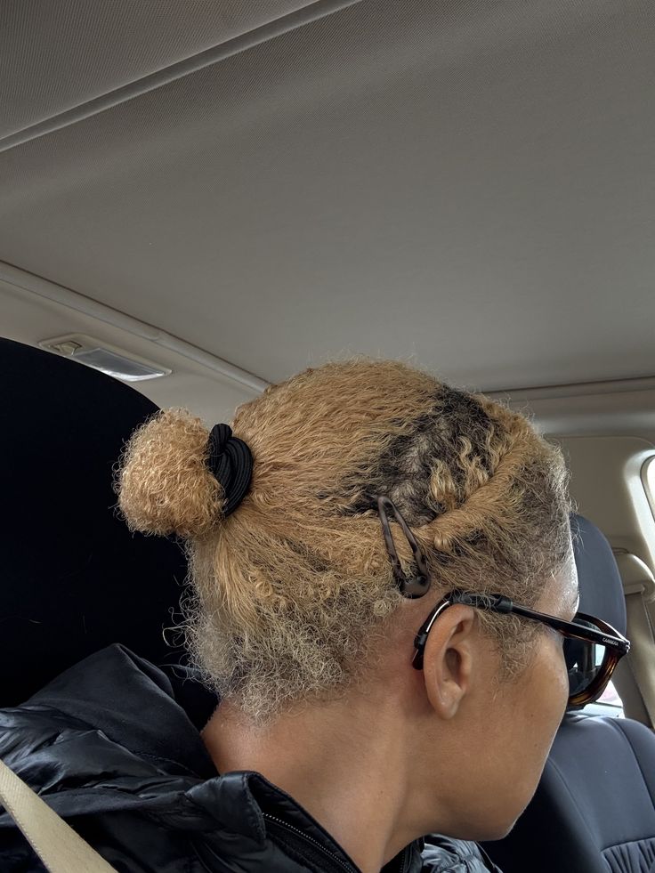 Woman caring for the ends of bleached 4C natural hair by tuvking it into a bun