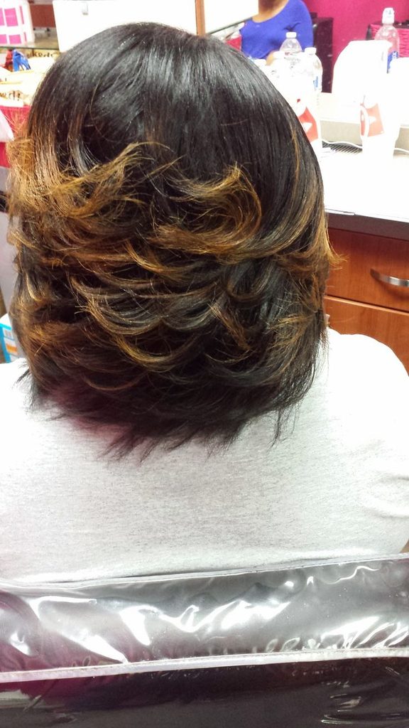 Woman styling transitioning hair to blend natural roots with relaxed ends