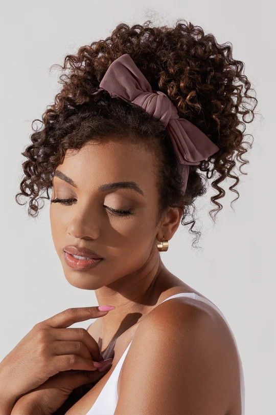Woman wearing a bow headband with natural hair