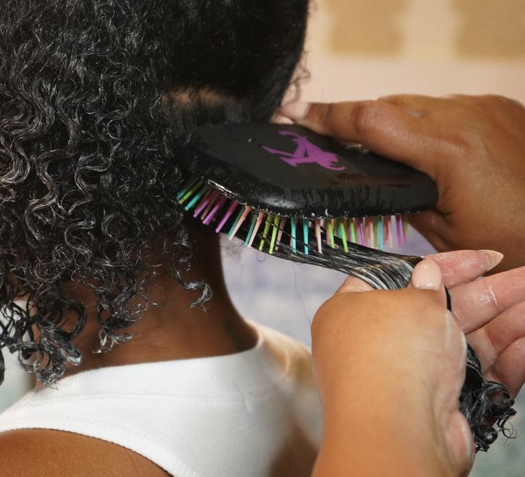Woman gently detangling textured transitioning hair