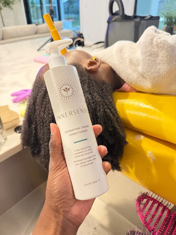 Parent applying conditioner while detangling a child's 4C hair as part of wash day routine