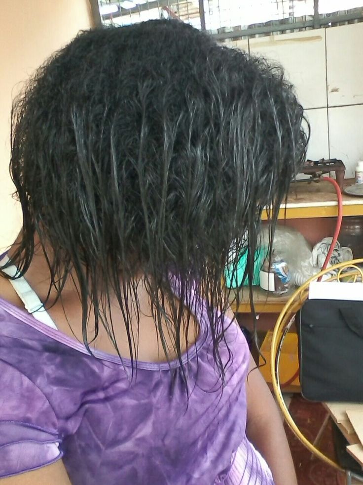 Woman examining relaxed ends during a natural hair transition