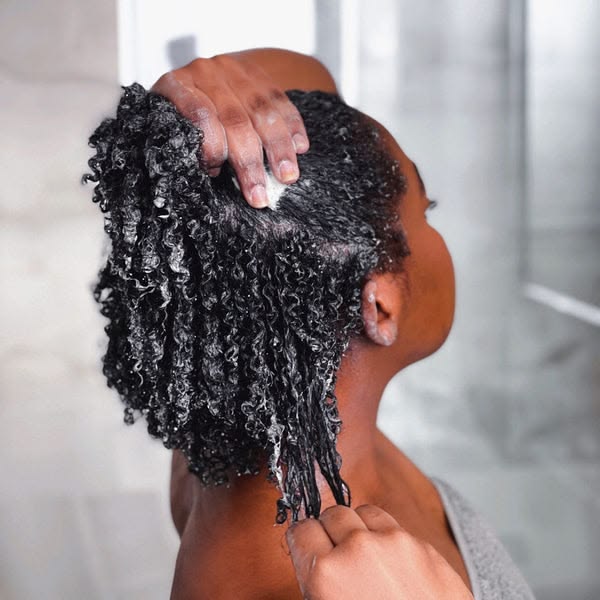 Woman deep conditioning natural 4C hair during fall