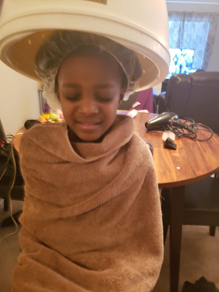 Child receiving a deep conditioning treatment for 4C hair