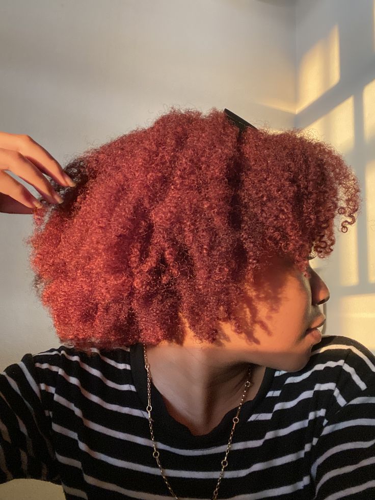 Black woman wearing deep red natural hair color for dark skin
