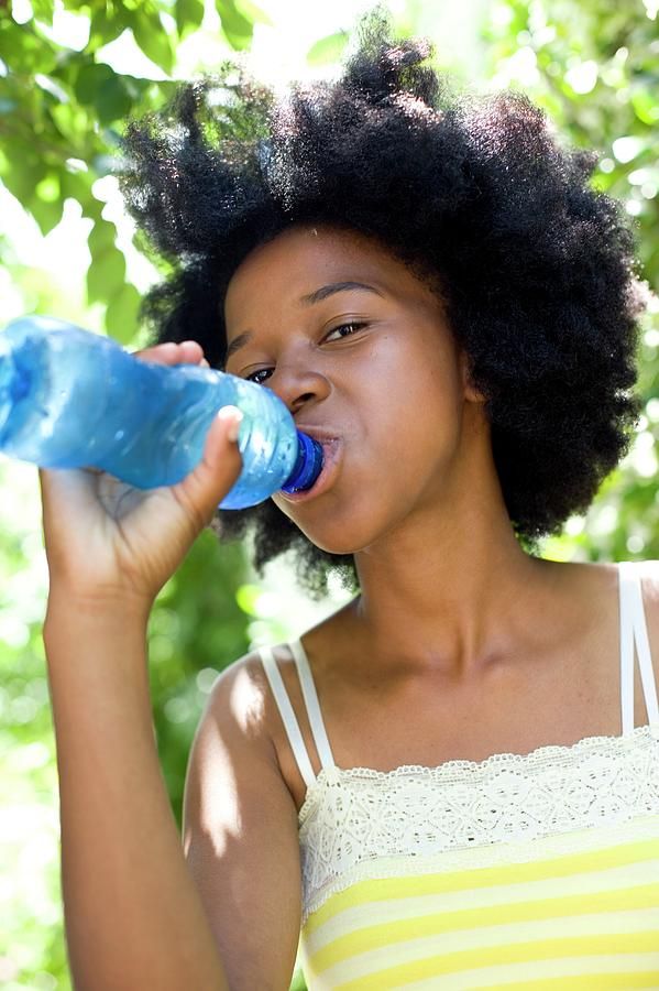 black woman with 4c hair drinking water for hair growth