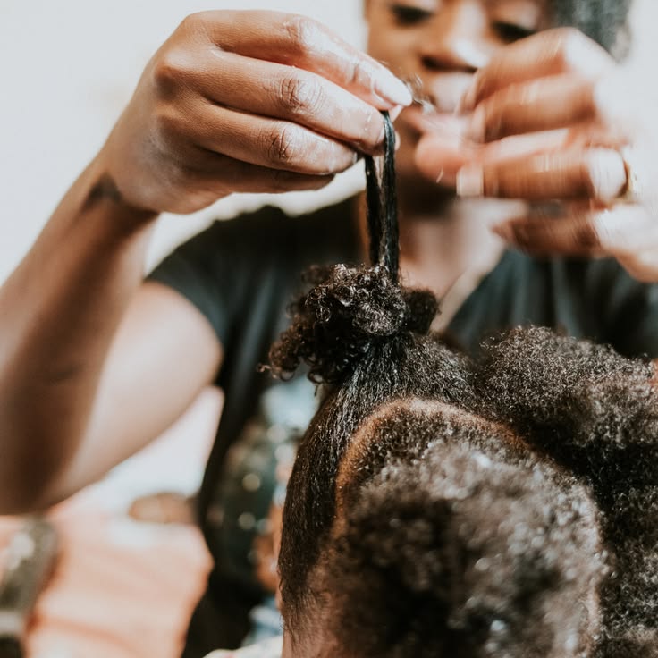 Parent using fingers to gently separate tangled strands in a child's 4C hair