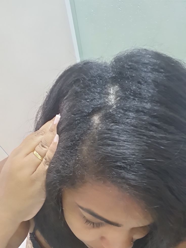 Woman examining new natural hair growth during the early stages of transitioning