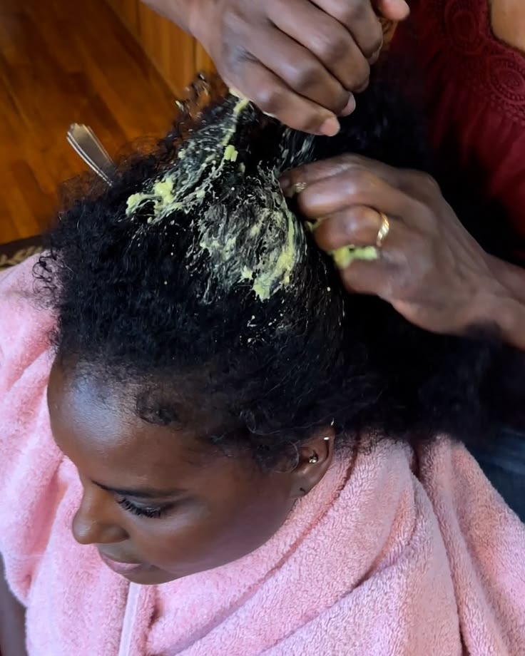 Woman applying a hair mask to natural 4C hair during fall