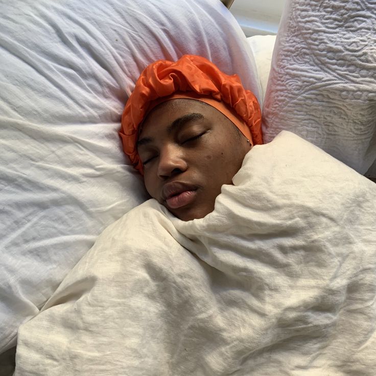 a woman wearing silk bonnet to protect her hair while sleeping