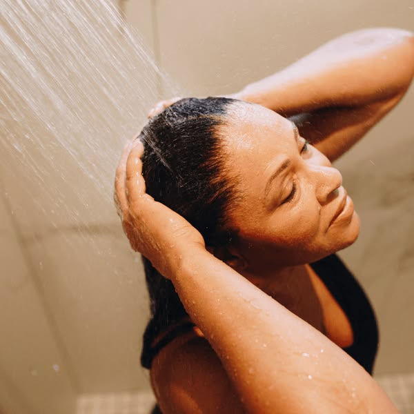 woman rinsing her thoroughly after shampooing