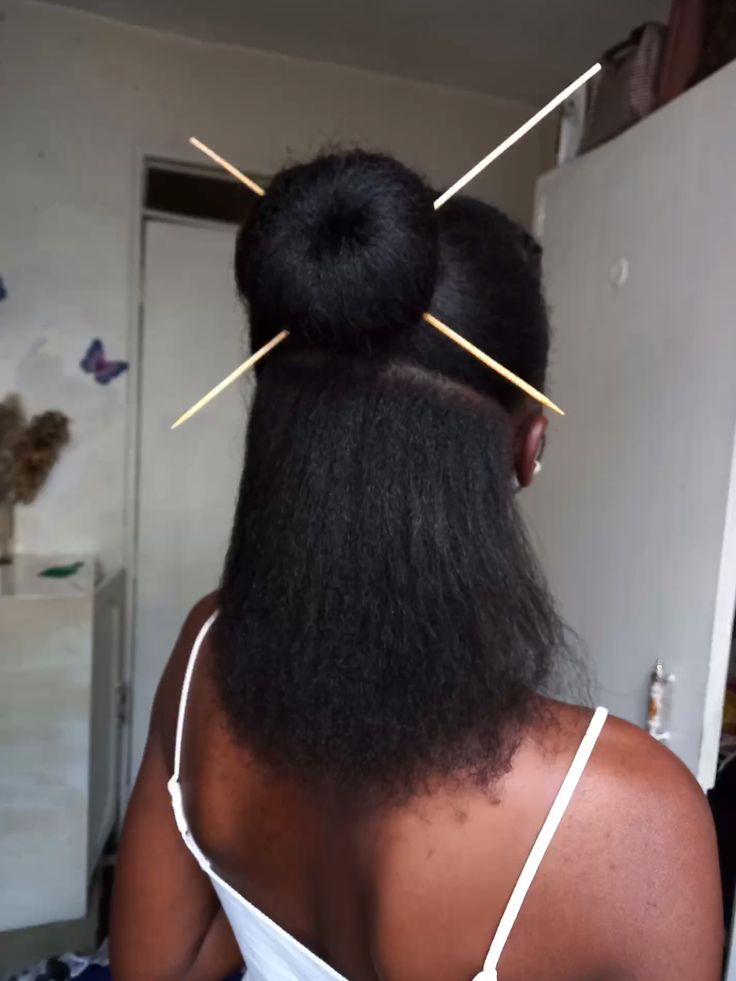 Woman wearing a natural hair bun secured with hair sticks