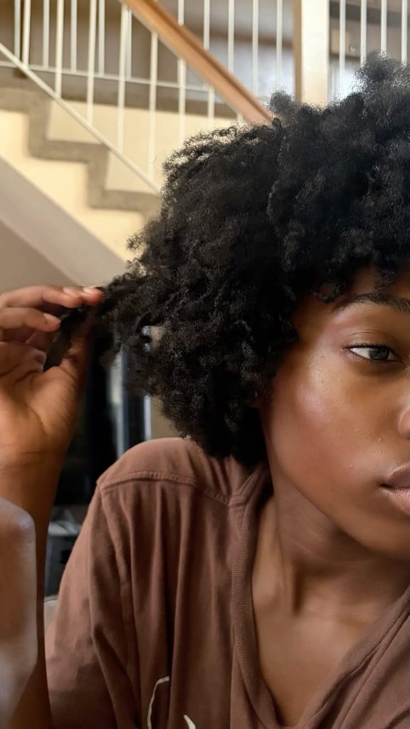 Woman examining healthy natural 4C hair during a summer routine