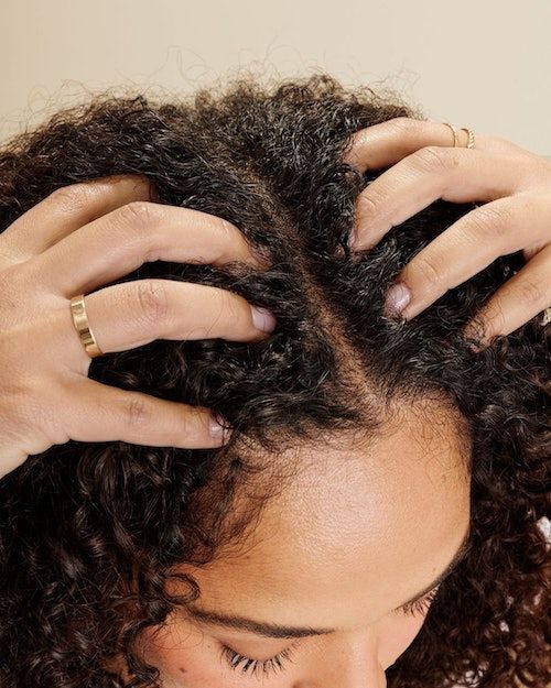 Woman gently massaging her scalp while caring for natural hair