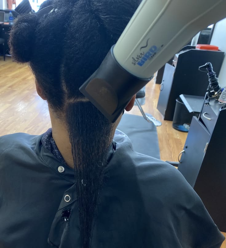 Woman using a blow dryer with heat protectant on transitioning hair