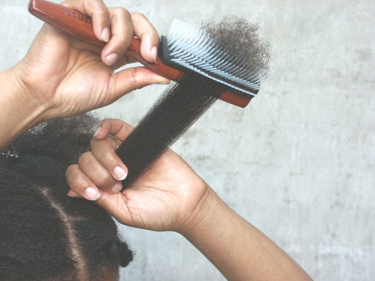 Parent holding a child's hair near the roots while gently detangling the ends
