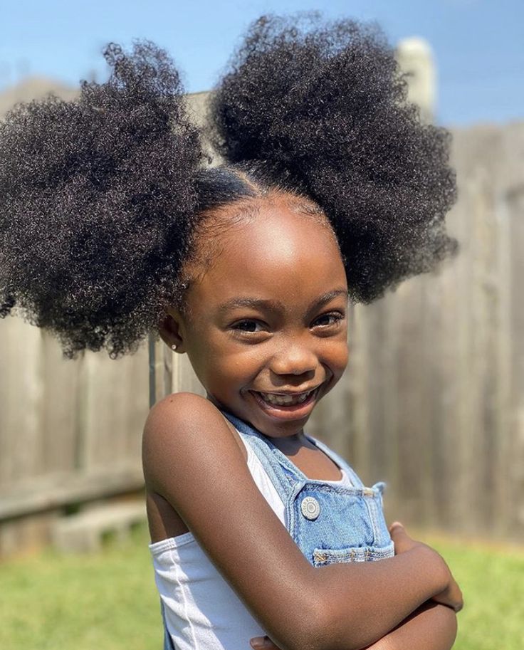 Black little girl with natural 4C hair styled in two fluffy side puffs
