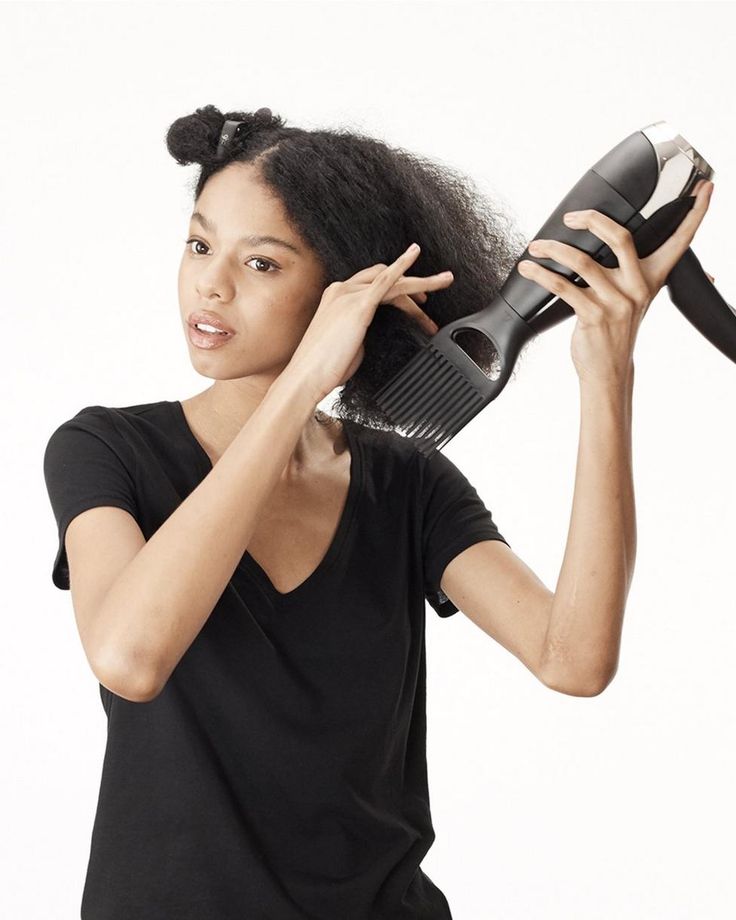 Woman using a blow dryer on low heat while stretching 4C hair gently