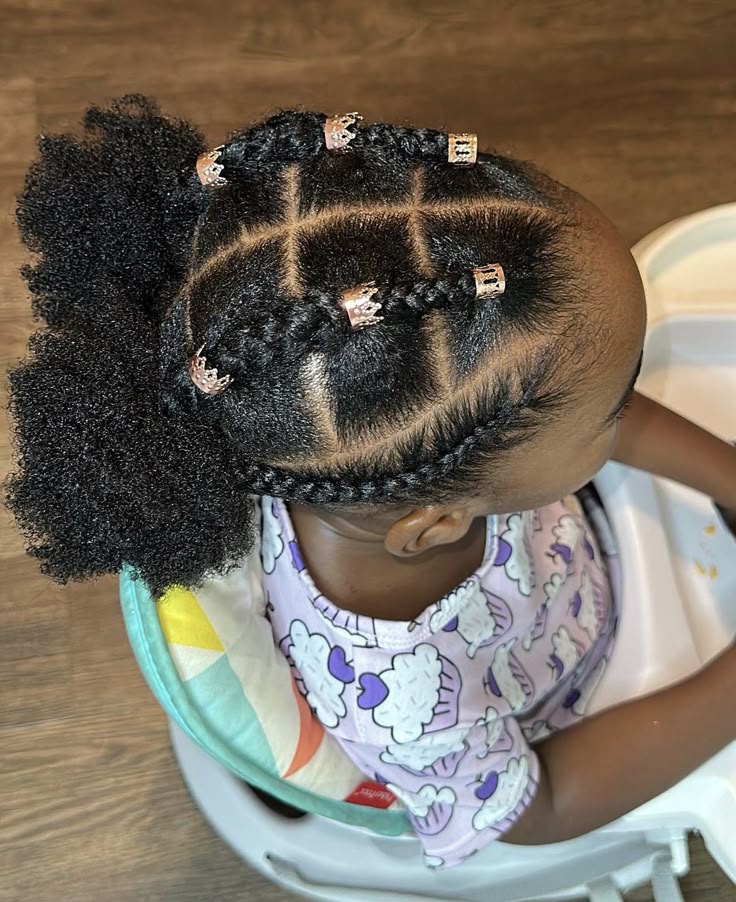 Child wearing two low natural hair puffs with braided sections