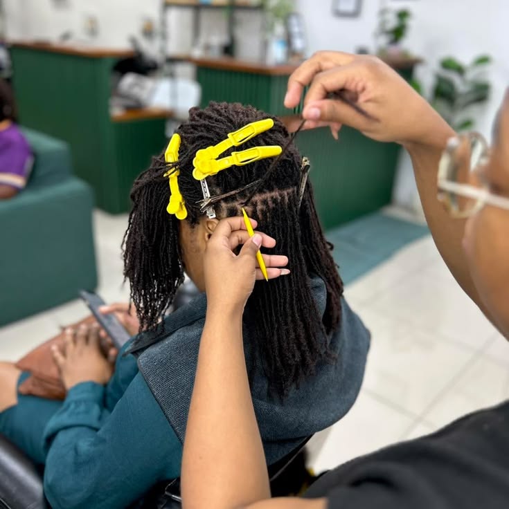 Professional maintaining small locs at the roots during an appointment