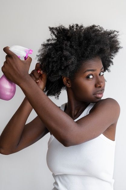 Woman applying a lightweight moisturizer to natural 4C hair