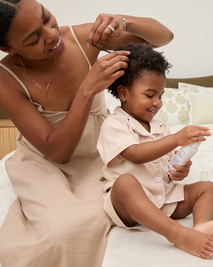 Parent applying conditioner to damp child's 4C hair before detangling
