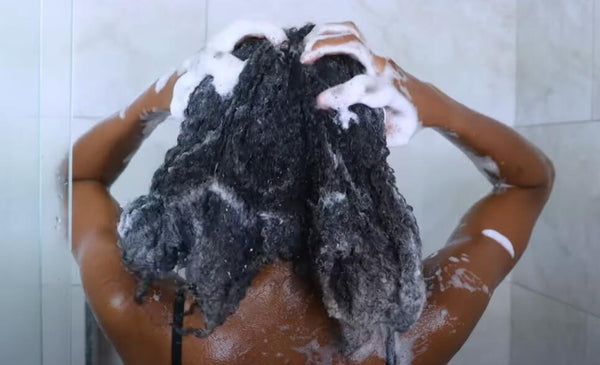Woman washing thick natural 4C hair during rainy season