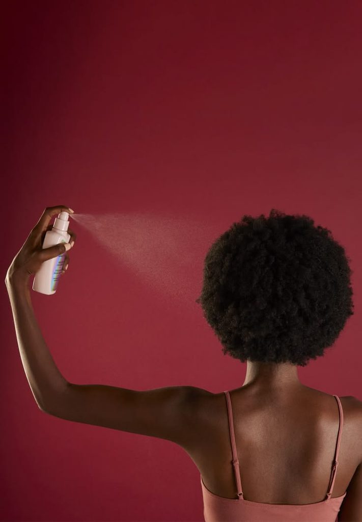 Woman lightly refreshing natural 4C hair between wash days
