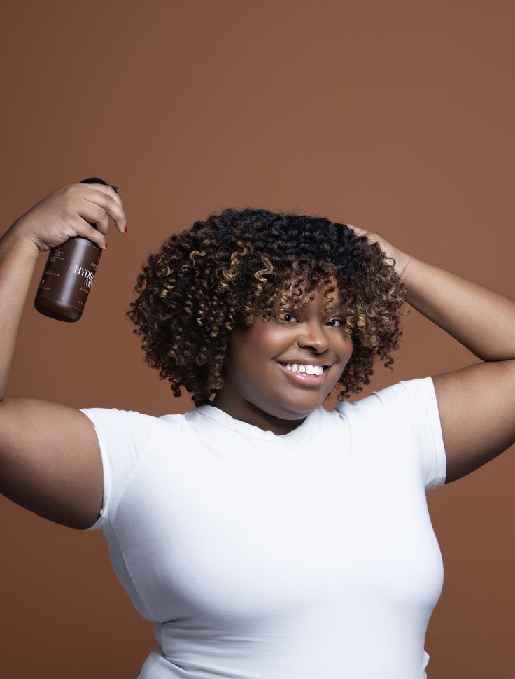 Woman refreshing dry 4C hair with a spray bottle between wash days