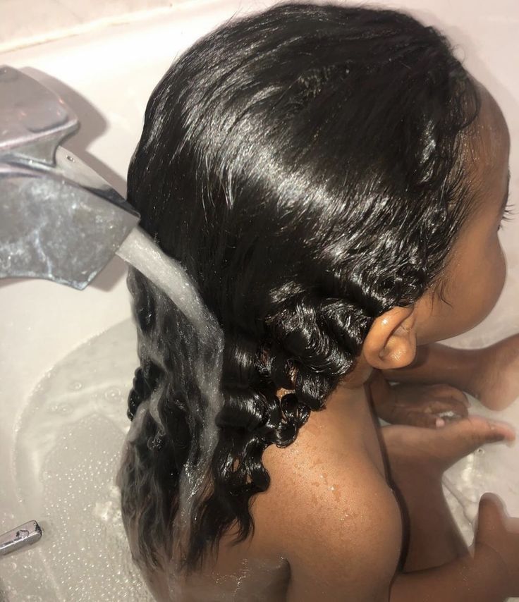 Parent gently rinsing a child's natural 4C hair after conditioning as part of wash day routine