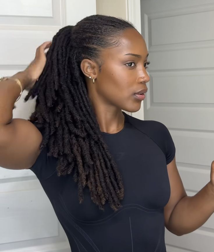 Woman styling her natural locs into an elegant hairstyle