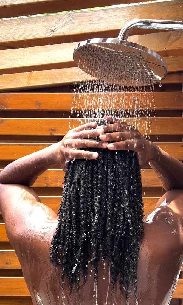 Woman washing natural 4C hair with comfortable warm water