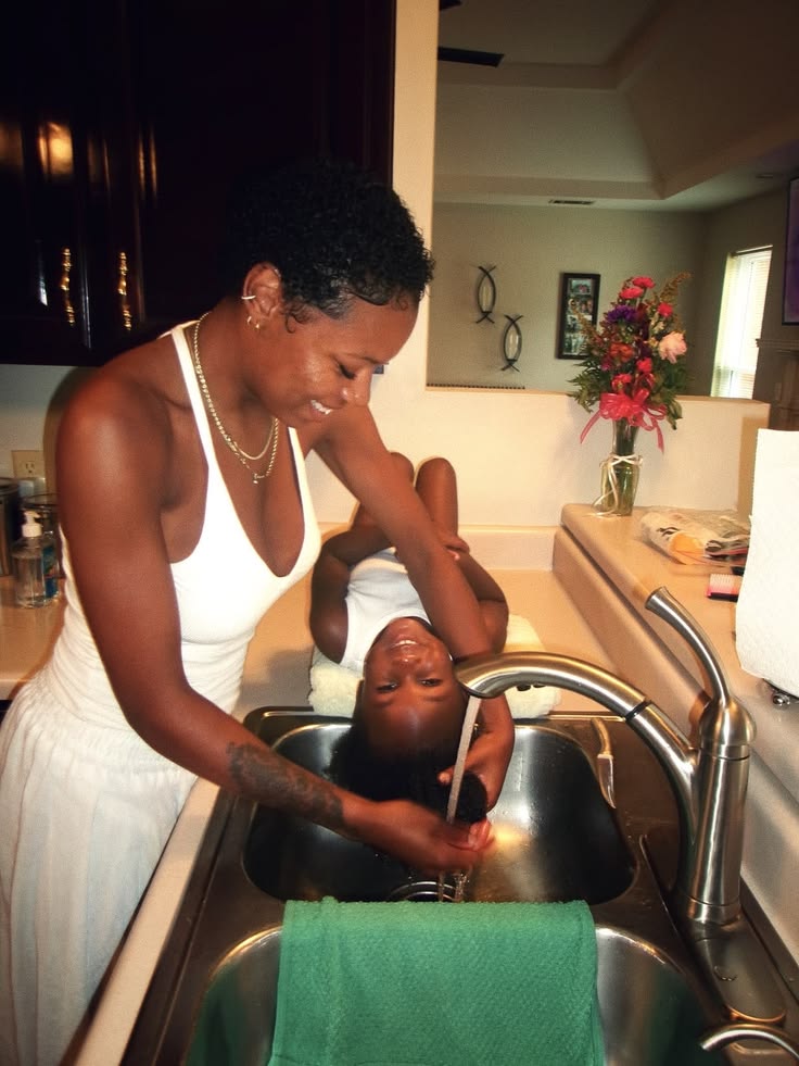 Child's 4C hair being gently saturated with water before shampooing