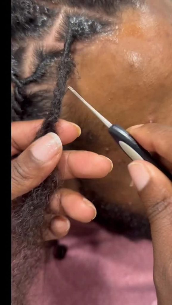 Loctician manually forming an instant loc on tightly coiled hair
