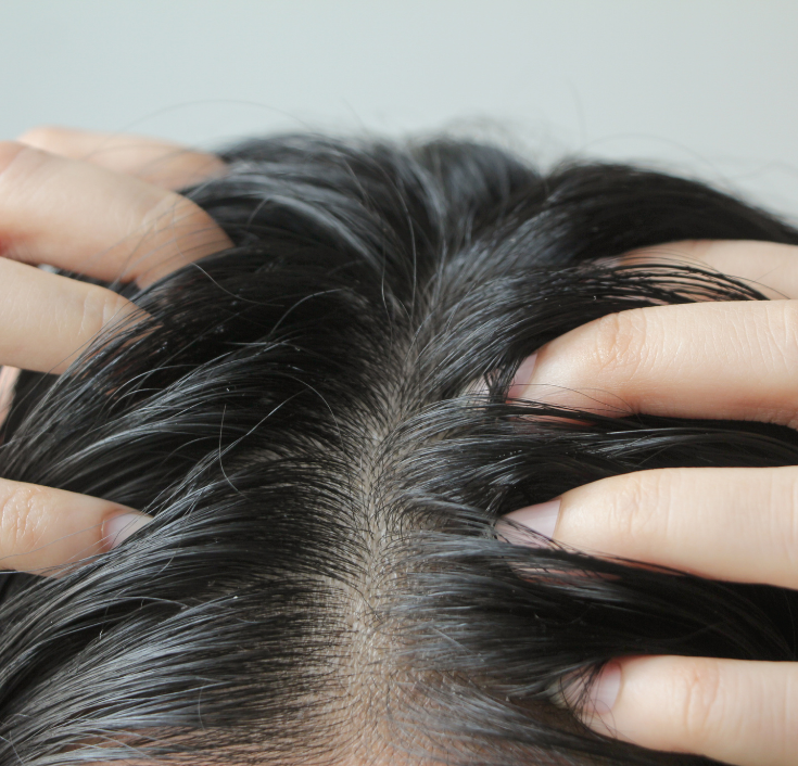 Close-up of hands gently massaging a natural hair scalp.